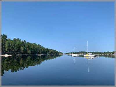 Two sailboats anchored on the lake for the 2021 August newsletter.